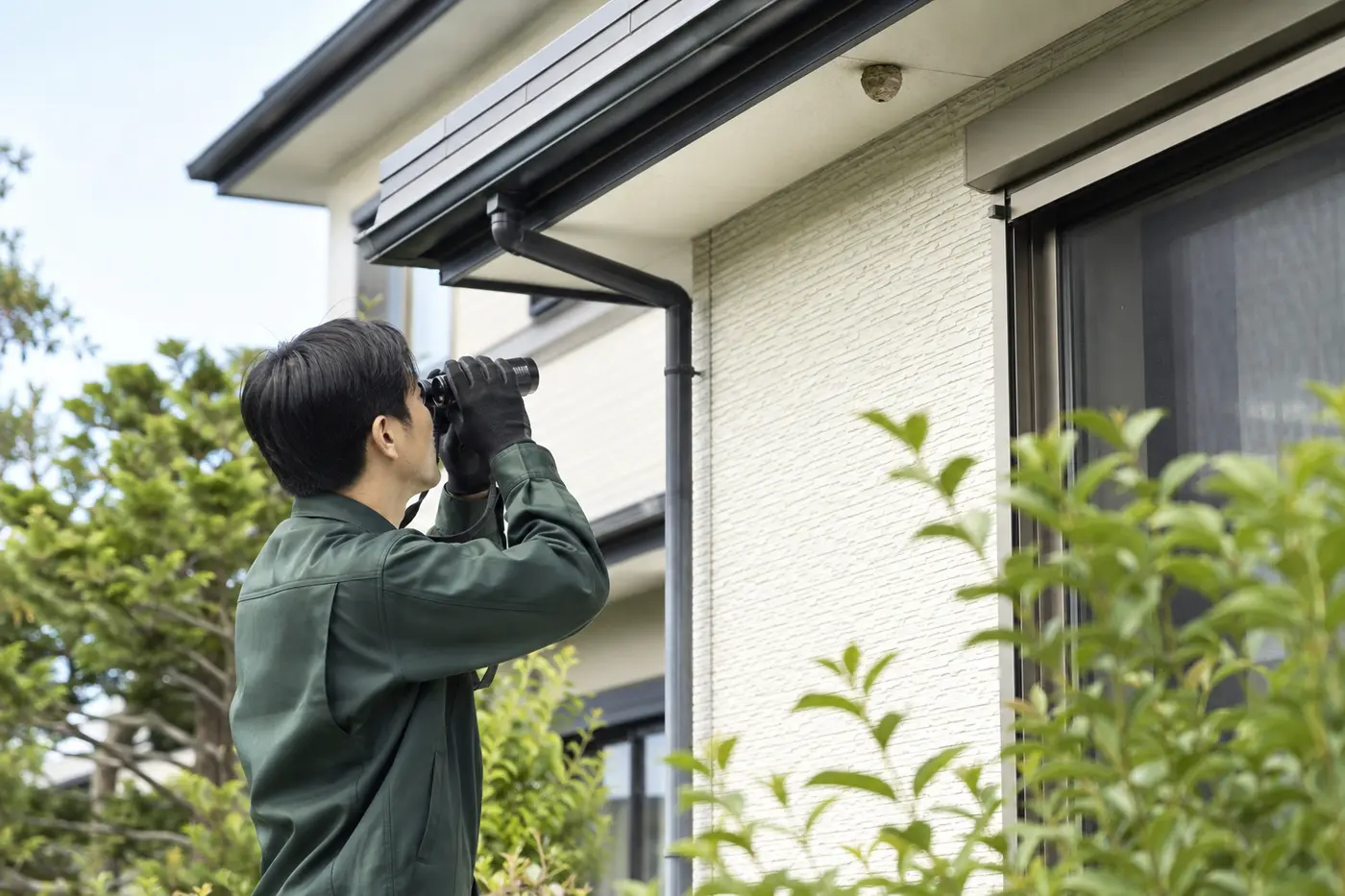 軒下のハチの巣を安全な距離から確認するスタッフの施工イメージ